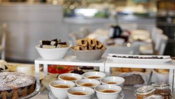 A buffet table with various food items including a cake, bowls of what appears to be a powdered substance, and jars of preserves.