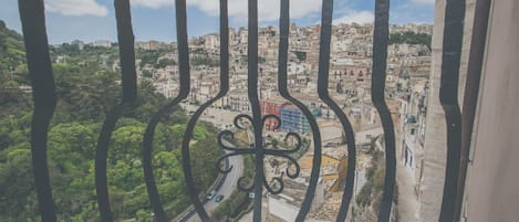 Vista desde un balcón con barandilla de hierro forjado, que domina una zona urbana densamente poblada con edificios y áreas verdes.