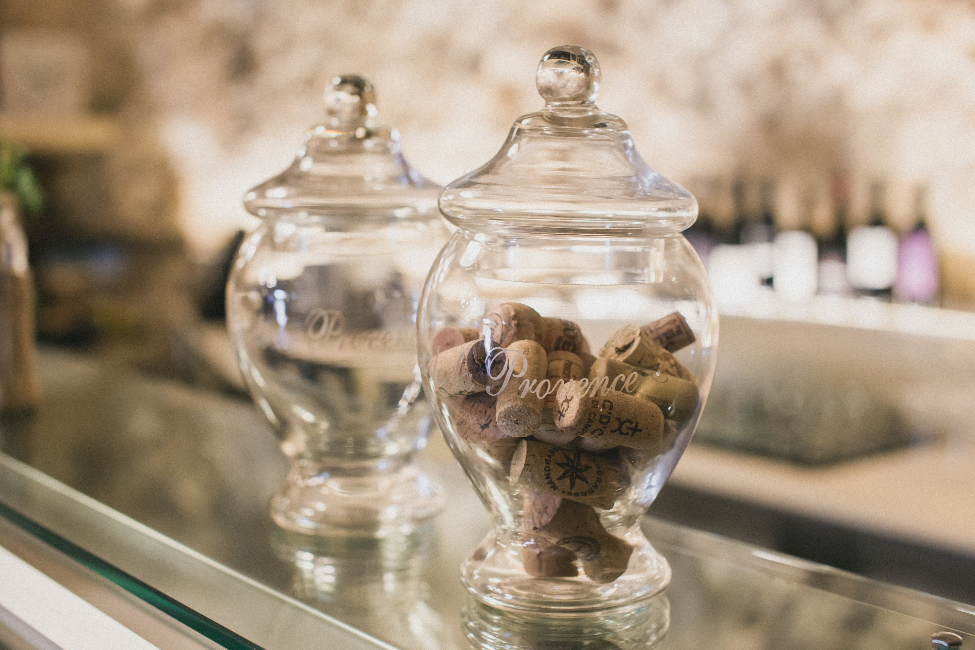 Two glass jars with corks on a reflective surface, likely a bar area.