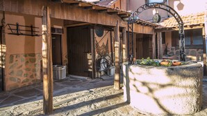 Une cour rustique avec un mur en pierre, des poutres en bois et un portail en métal.