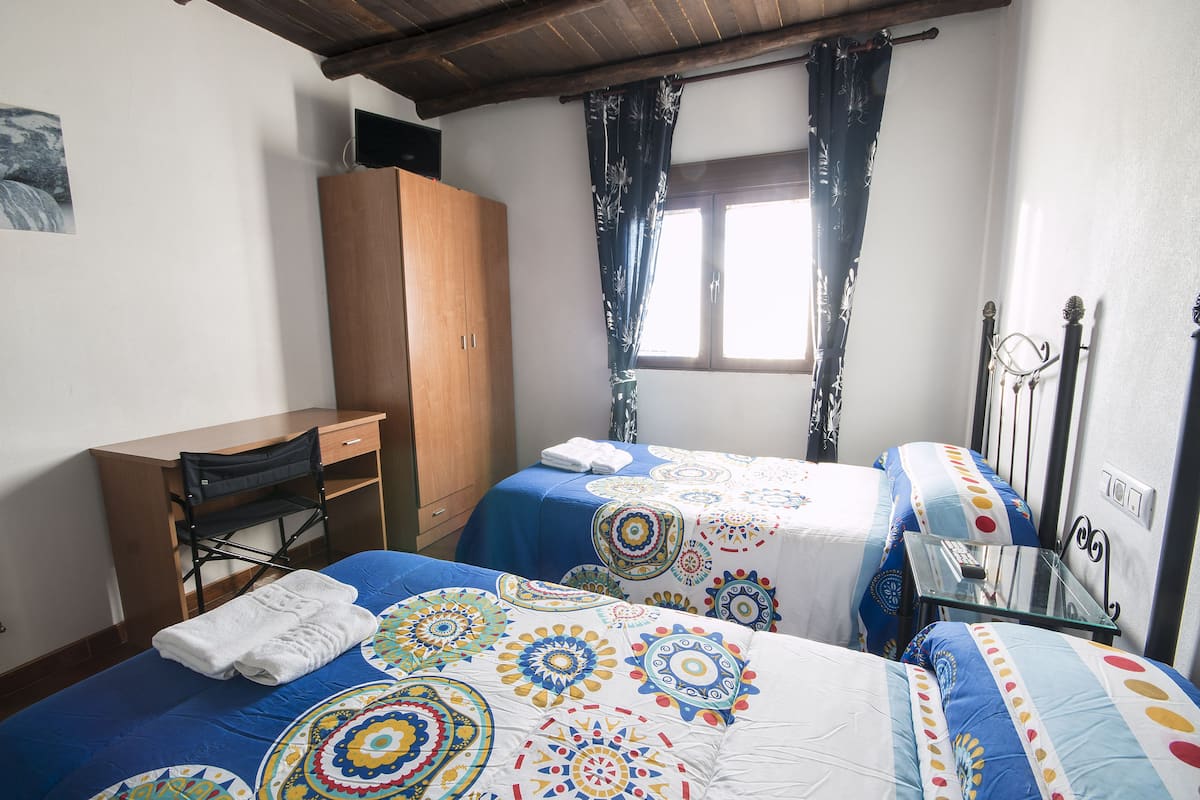 Une chambre avec deux lits, un bureau en bois et une armoire.