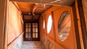 Un escalier avec des marches en pierre et des rampes en bois, menant à une porte dotée de panneaux de verre.