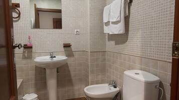 A bathroom with a sink, toilet, and bidet.
