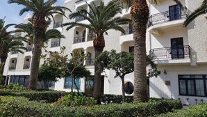 A multi-story building with balconies, palm trees, and a well-maintained garden. - Hotel Club Costa Elisabeth (Ciro)