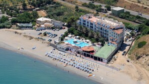 An aerial view of a coastal hotel with a swimming pool, beach umbrellas, and a tennis court. - Hotel Club Costa Elisabeth (Ciro)