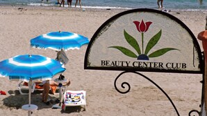 A beach with a sign reading "Beauty Center Club". There are beach umbrellas and lounge chairs. - Hotel Club Costa Elisabeth (Ciro)