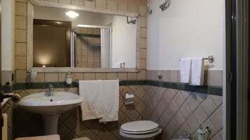 Ein Badezimmer mit Waschbecken, Toilette und Bidet. Über dem Waschbecken hängt ein Spiegel und an der Wand ist ein Handtuchhalter.