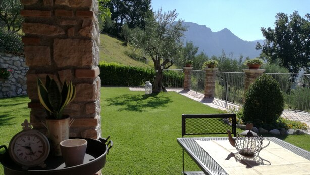 Un patio con una mesa, sillas, un reloj y plantas en macetas.