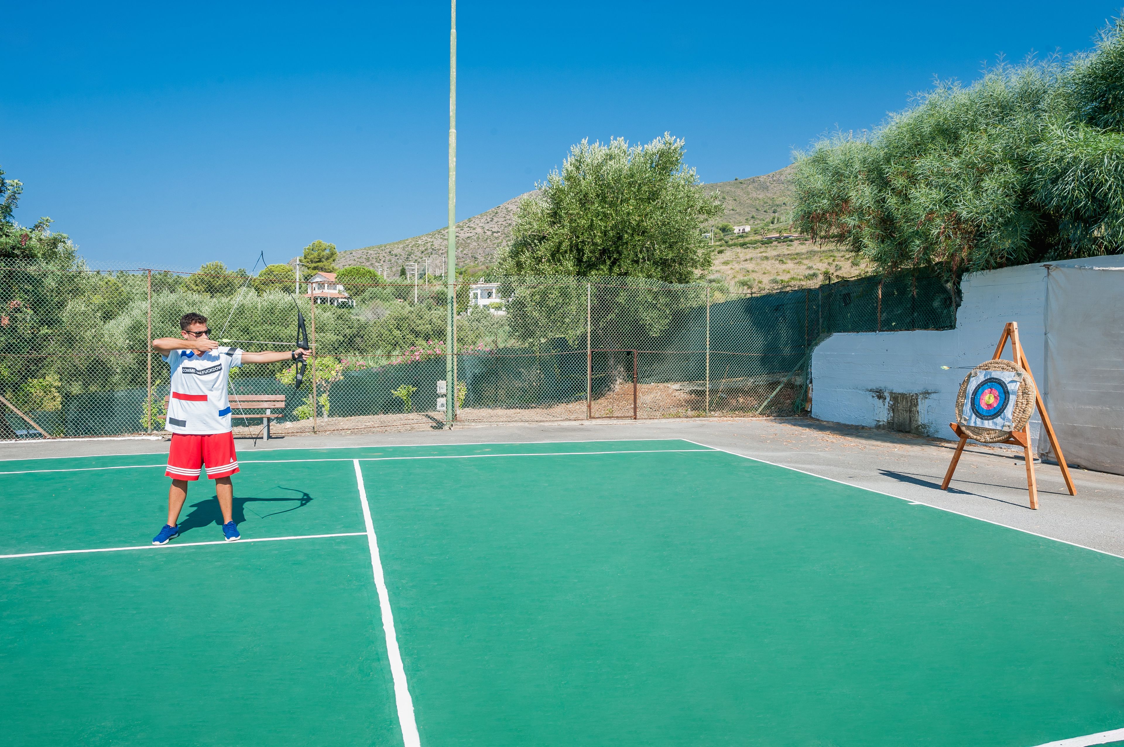 A tennis court with a net, a target board, and a fence.
