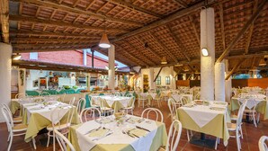 Un restaurante con varias mesas y sillas, piso de baldosas y techo de madera.