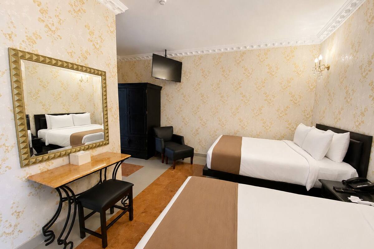 A hotel room with a bed, a desk, a chair, a television, and a wardrobe.