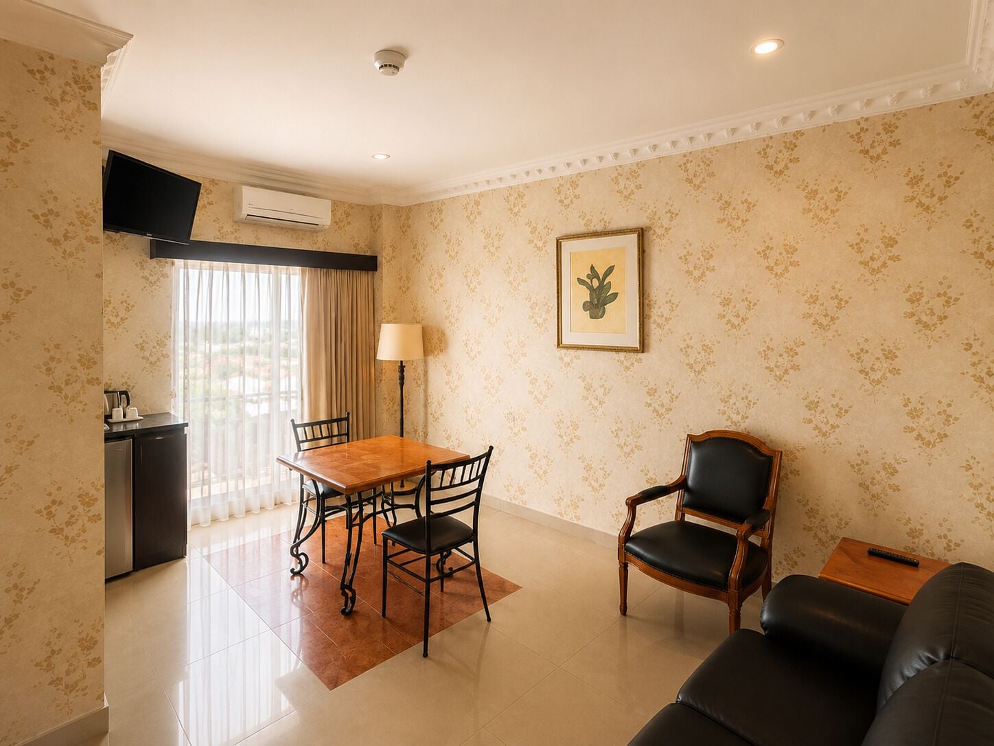 Habitación de hotel con una mesa de comedor, sillas, un sofá, un televisor, un aire acondicionado y un cuadro en la pared.