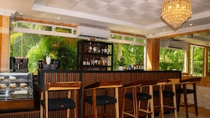 A bar area with wooden chairs, a counter with bottles, and a coffee machine. - Hotel Palacio Maya (Mérida)