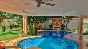 A swimming pool with a curved edge, surrounded by a tiled deck and outdoor furniture. - Hotel Palacio Maya (Mérida)
