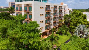 A multi-story hotel with balconies, surrounded by lush greenery and a clear sky. - Hotel Palacio Maya (Mérida)