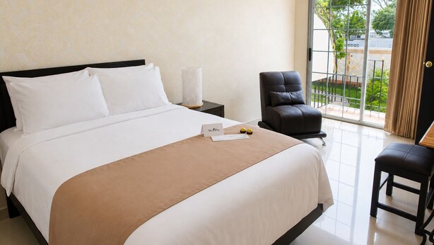 A hotel room with a bed, a desk, a chair, and a view of the outdoors.