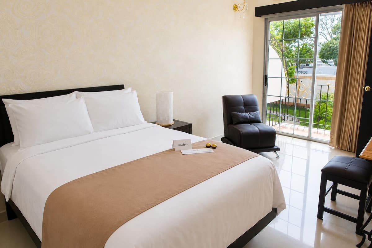 A hotel room with a bed, a desk, a chair, and a view of the outdoors.