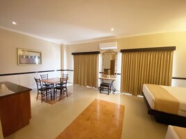 Ein Hotelzimmer mit Bett, Schreibtisch mit Stuhl, Schminktisch mit Spiegel und Esstisch mit Stühlen.