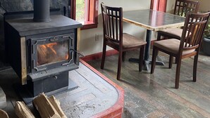 A dining area with a stone wall, a wood-burning stove, and a table with chairs.