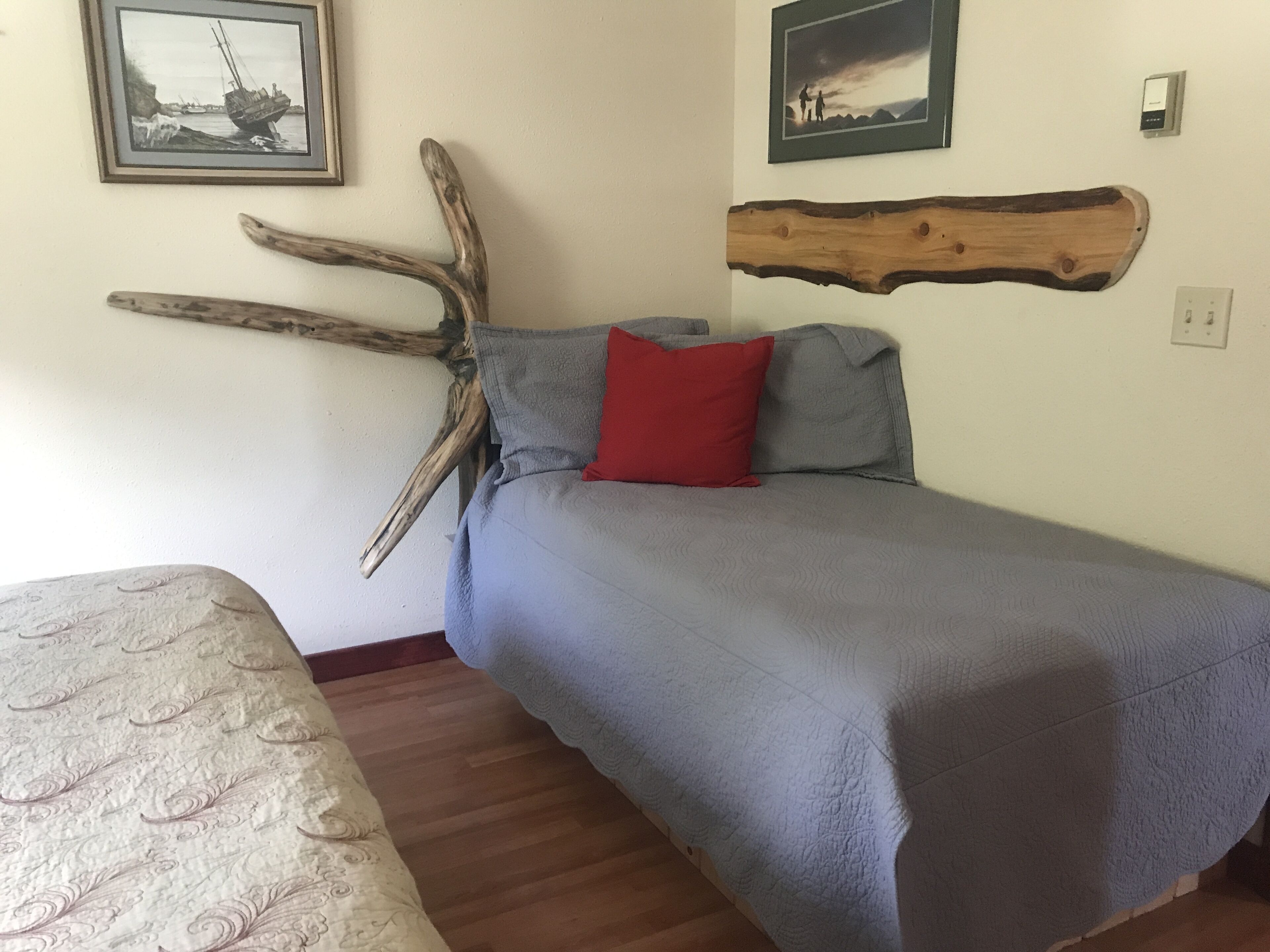 A bedroom with a bed, a wooden headboard, and two framed pictures on the wall.