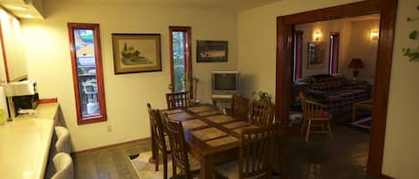 Un comedor con una mesa y sillas de madera, un televisor y cuadros en la pared.