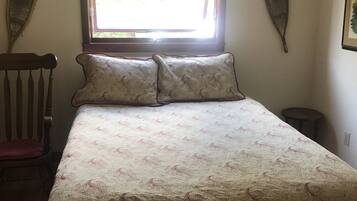 Quarto com cama, uma cadeira, janela e decorações nas paredes.