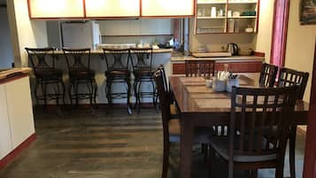 A kitchen with a dining table, four bar stools, and a refrigerator.