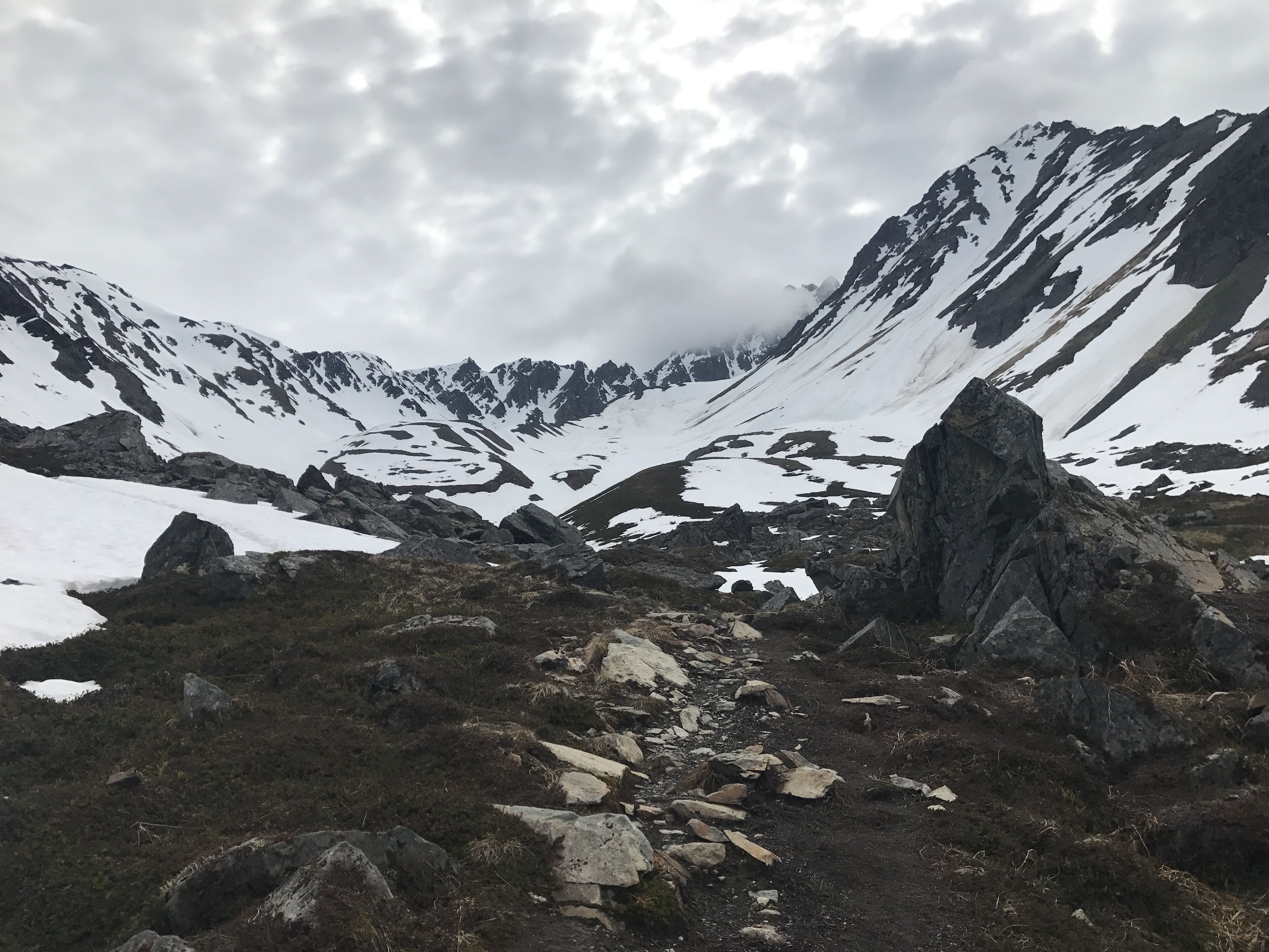 Un paysage montagneux accidenté, parsemé de plaques de neige et de rochers.