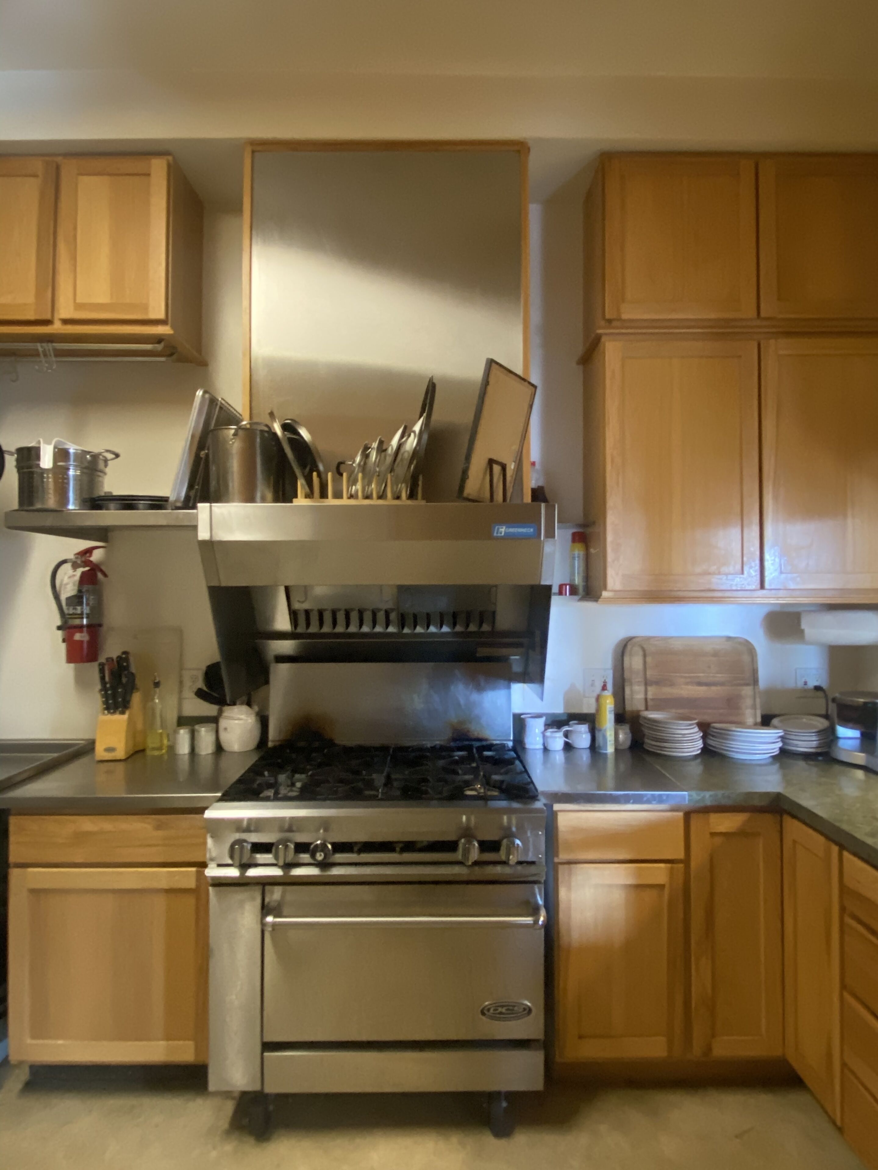 A kitchen with wooden cabinets, a stainless steel stove, and a range hood.