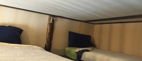 Een kleine, compacte kamer met twee eenpersoonsbedden, elk voorzien van een kussen en dekbed.