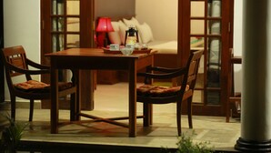 A wooden dining table with chairs, a red lamp, and a lantern on the table. - Temple Tree Hotel Weligama (Weligama)