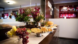 Un buffet proposant une variété de fruits, de gaufres et de viennoiseries.