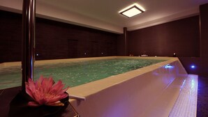 Une piscine décorée de motifs de fleurs de lotus, entourée de murs en bois foncé et dotée d’un éclairage encastré.