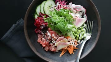 A bowl of sushi with various toppings including cucumber, radish, and greens.