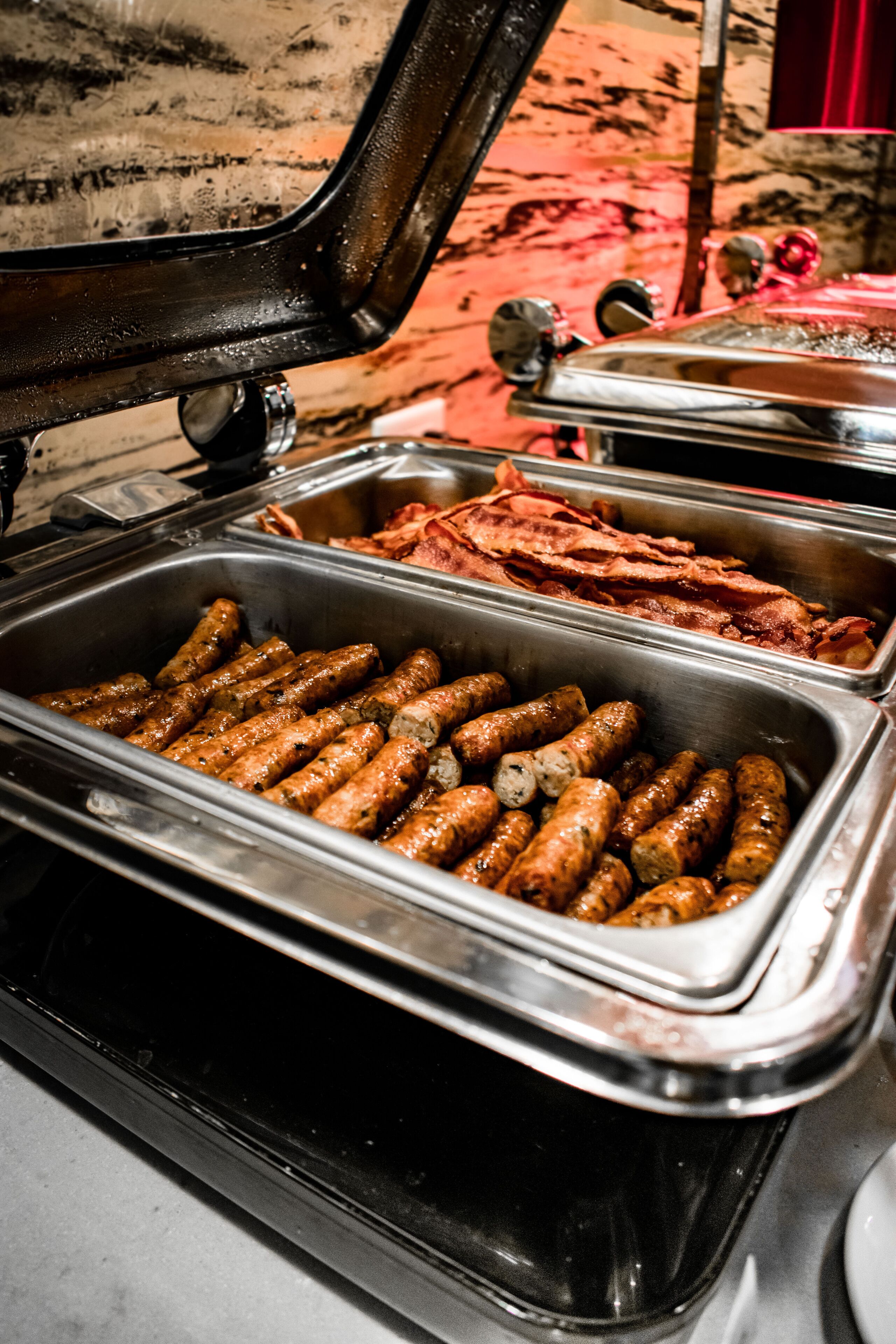 A buffet with various food items including sausages and bacon.