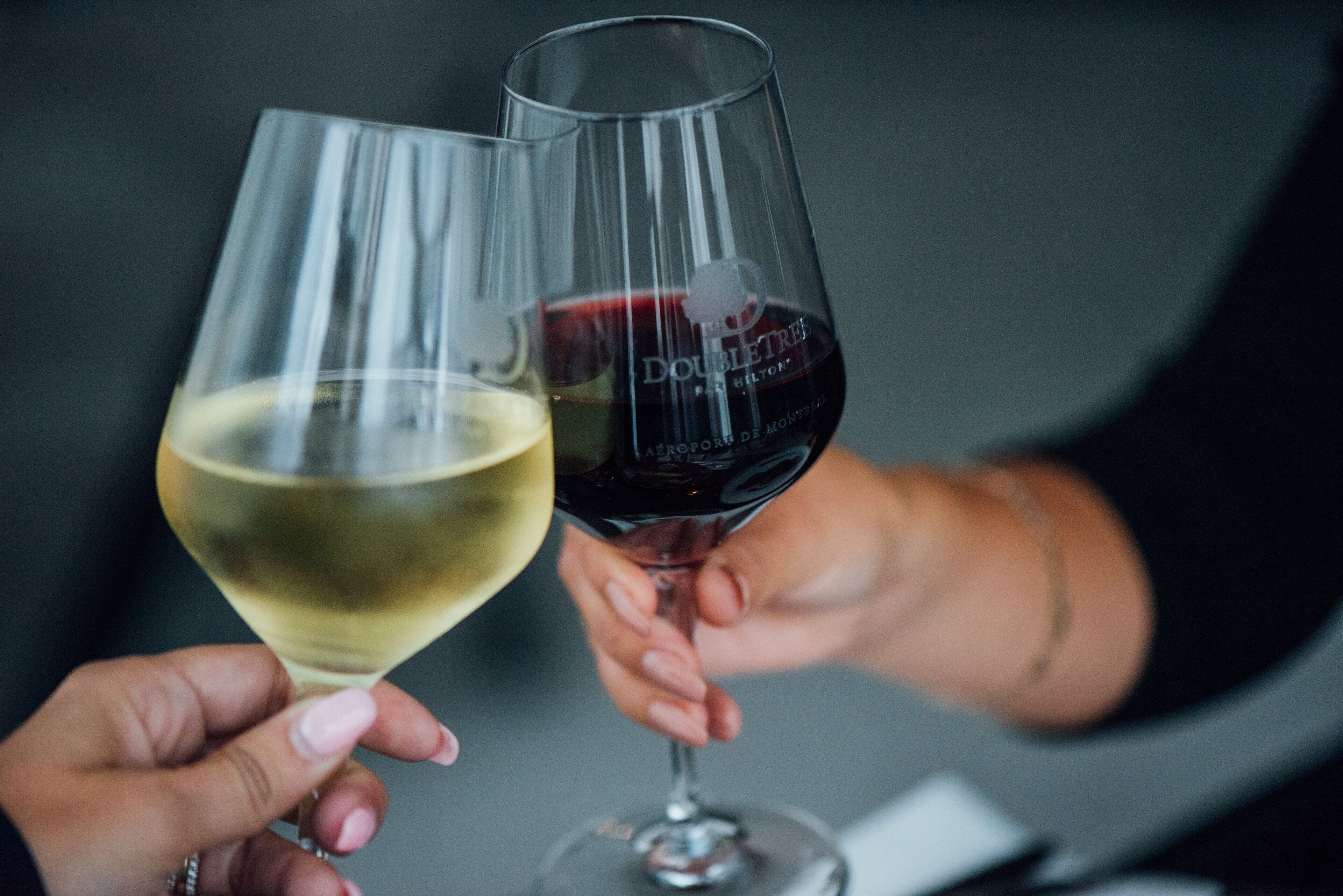 Two wine glasses, one with white wine and the other with red wine, held by a person.