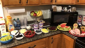 A kitchen with wooden cabinets, a microwave, and various food items on the counter.