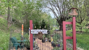 A garden gate labeled "NATIVE PLANTS" with a rustic bell and decorative elements.