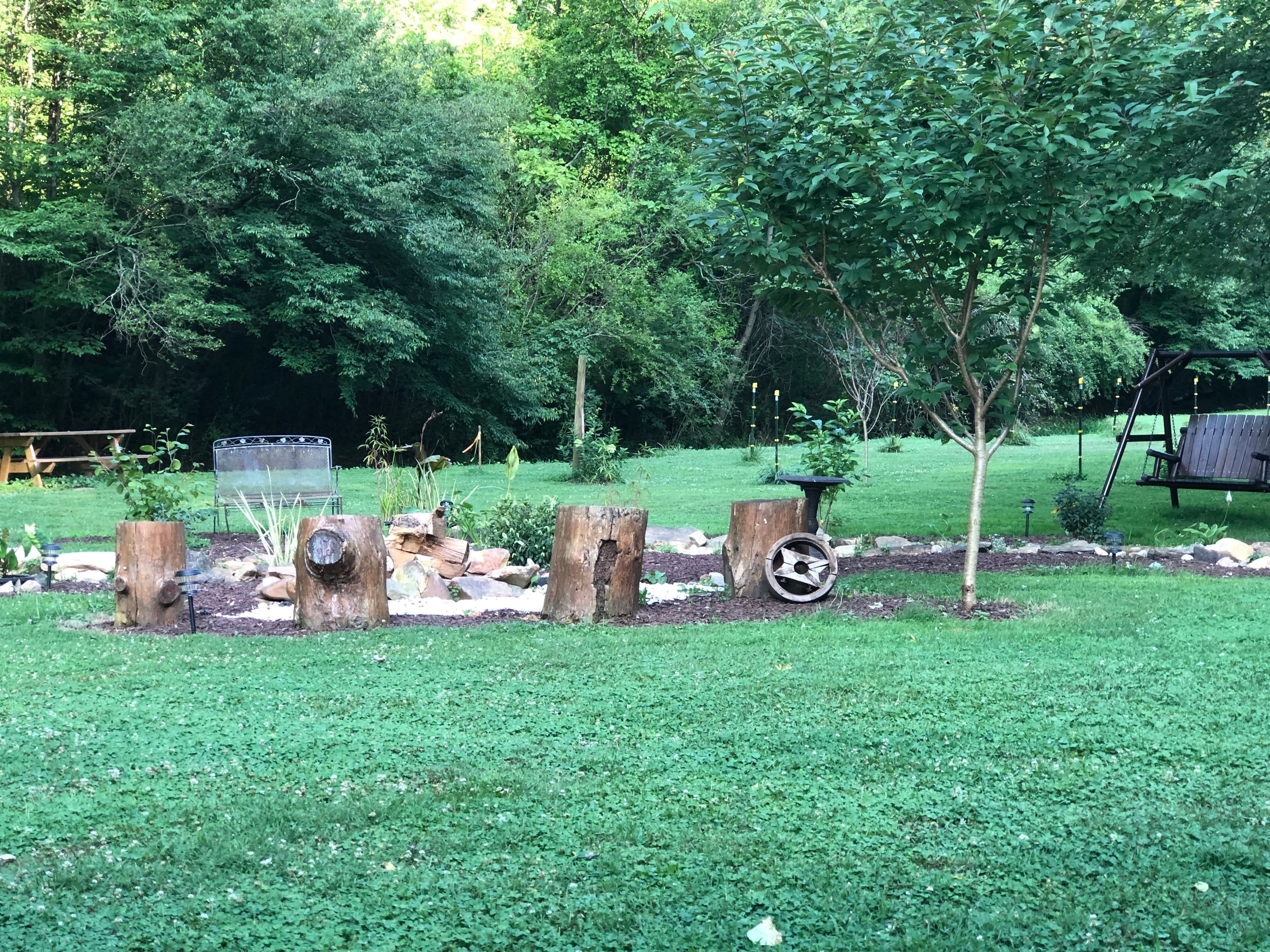 A garden with a wooden bench, a swing set, and a bird feeder.