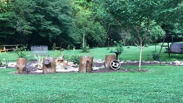 A garden with a wooden bench, a swing set, and a bird feeder.