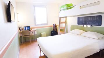 Ein Hotelzimmer mit Etagenbett, Schreibtisch, Stuhl und Fenster.