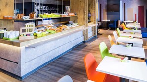 Una cafetería moderna con una barra amplia, zona de estar y diversas opciones de comida y bebida.