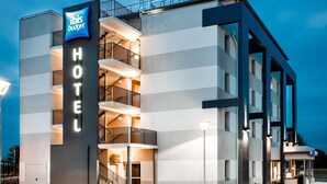 Un hotel moderno con un llamativo letrero de 'ibis budget', varios balcones y una entrada bien iluminada.