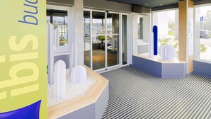 Un moderno vestíbulo de hotel con mostrador de recepción, zona de estar y grandes ventanales con vistas al estacionamiento.