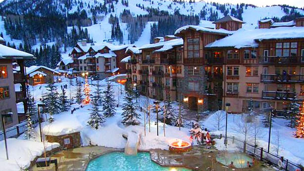 Un resort con varias edificaciones, un área de piscina central y paisajes nevados.