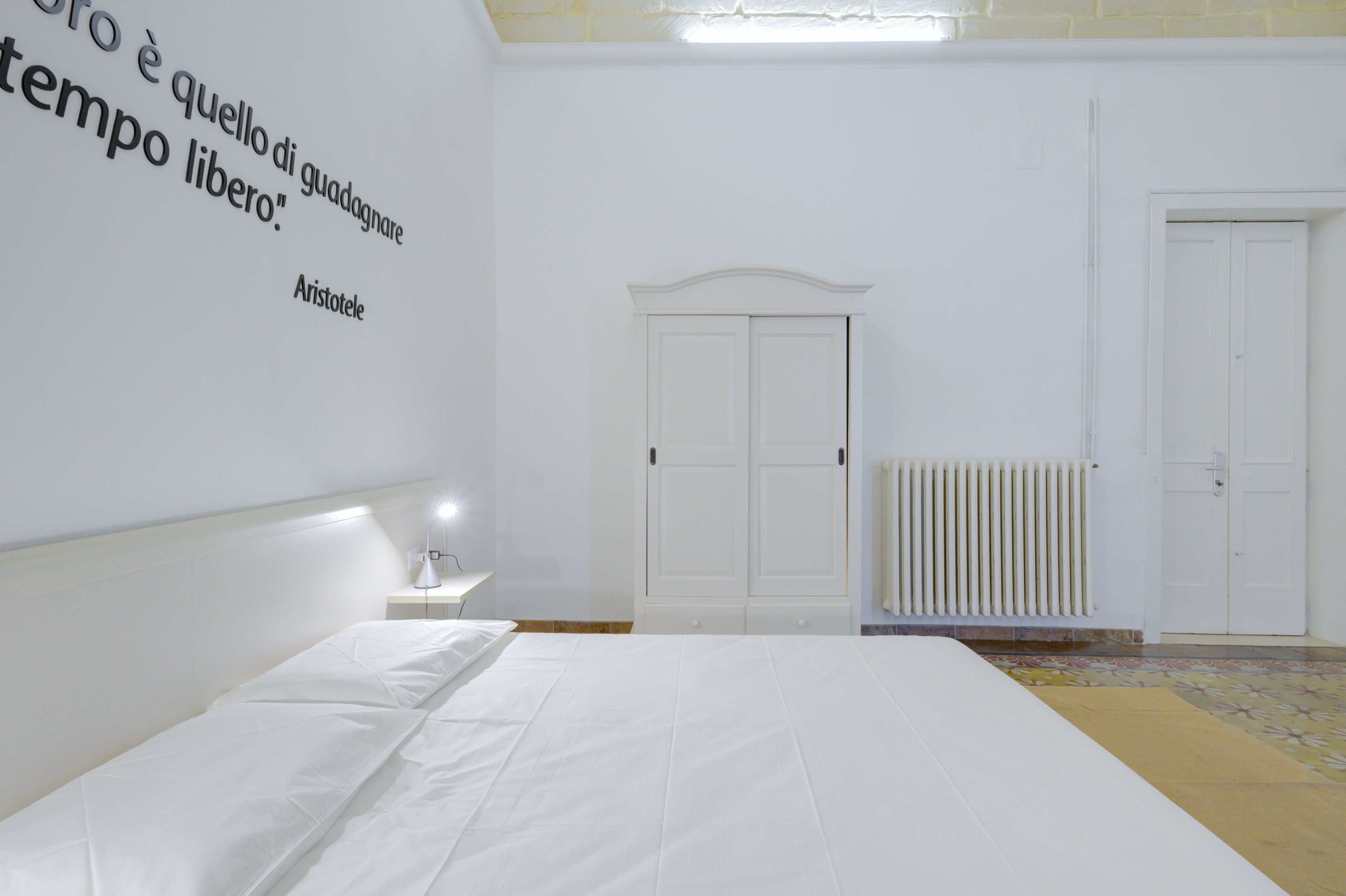Un dormitorio minimalista con una cama, un armario y un radiador.