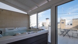 A spa area with a large hot tub and a balcony with outdoor furniture. - Ada Suites (Lecce)