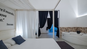 A modern bedroom with a large bed, a bathtub, and a quote on the wall. - Ada Suites (Lecce)