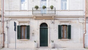 A building with a green door, two windows with shutters, and a balcony with plants. - Ada Suites (Lecce)