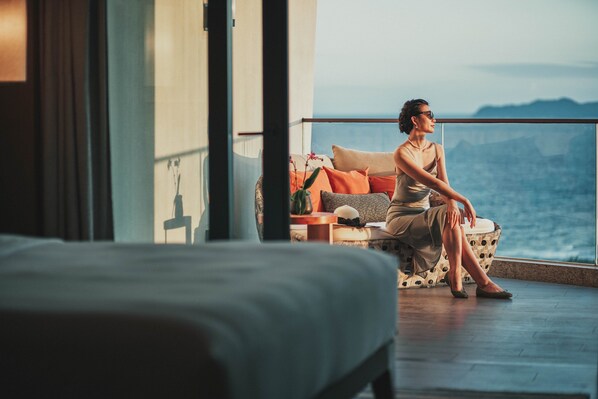 A person sitting on a balcony with a view of the sea.